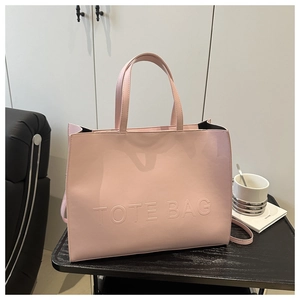 Detailed view of pink leather tote bag with embossed lettering on a textured surface