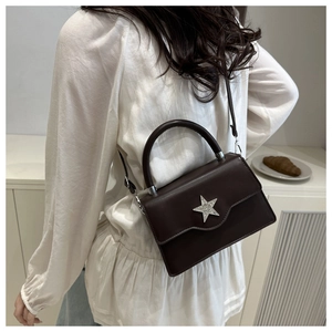 Sac bandoulière marron avec étoile argentée porté par un mannequin dans un style de vie