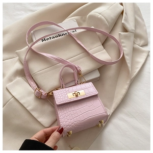 Detail of pink croc-textured mini bag with gold hardware and protective metal feet