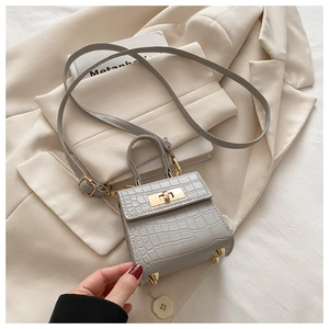Macro shot of grey stone-patterned leather texture and golden metal feet on the bag