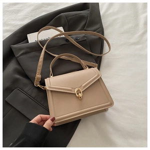 Detail of khaki leather handbag featuring an elegant gold ring buckle and envelope flap