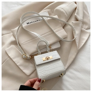 Detailed view of white crocodile embossed mini bag with gold hardware and bottom studs