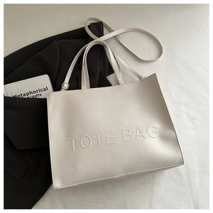 Detail of cream tote bag with embossed lettering and detachable long shoulder strap