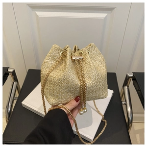 Détail du sac seau en paille avec chaîne dorée et élégants cordons à perles