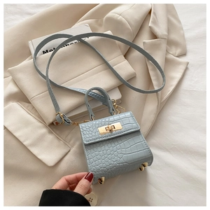 Detail of light blue crocodile embossed leather mini bag with golden twist lock
