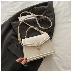 Detail of cream white leather bag showing the golden interlocking chain buckle and handle