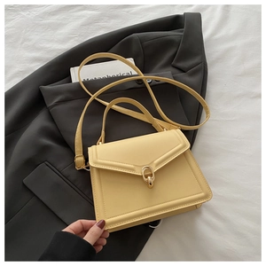 Detail view of bright yellow faux leather handbag with gold U-shaped metal lock and handle
