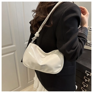 Détail d'un sac demi-lune blanc crème avec bandoulière nouée et cuir synthétique brillant