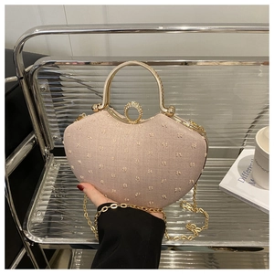 Detail of champagne gold heart clutch bag with rhinestone ring lock and metal handle