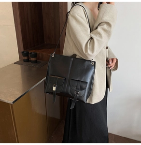 Close-up of black retro PU leather tote bag featuring dual front pockets and metal buckles