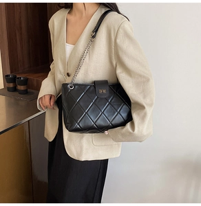 Detailed shot of a black quilted tote bag with a chain strap and metal swivel lock