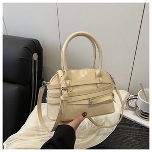 Close-up of beige Boston bag featuring decorative multi-belt straps and metallic buckles