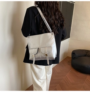 Detail of silver metallic tote bag featuring dual front flap pockets and wide shoulder strap