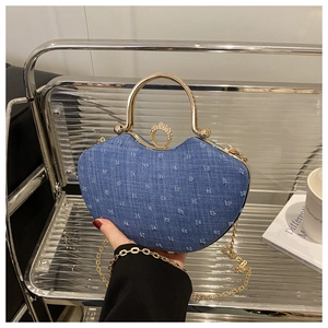 Detailed view of heart-shaped denim handbag with gold metal handle and diamond lock