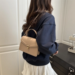 Minimalist beige leather shoulder bag with gold twist lock shown on a model