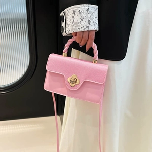 Pink patchwork square bag with golden flower clasp and braided handle shown on a model