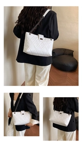 Macro detail of white quilted tote bag featuring metal chain strap and turn-lock closure