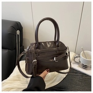 Detail of dark brown vintage faux leather handbag with belt buckle and metal hardware