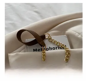 Detail of vintage shoulder bag featuring a brown leather and gold chain strap