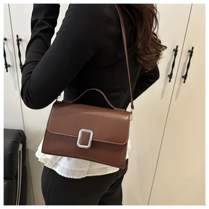 Sac bandoulière marron en similicuir avec boucle argentée porté par un mannequin