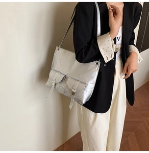 Detail of silver metallic shoulder bag with double front flap pockets and straps