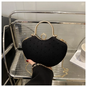 Detail of black shell-shaped clutch bag with gold handle and sparkling rhinestone buckle
