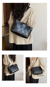 Detail of quilted black tote bag with metal chain strap and twist-lock closure
