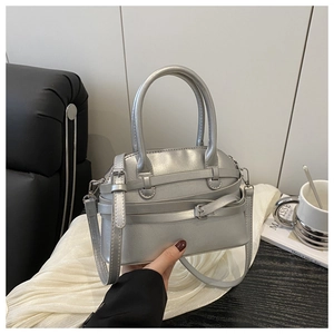 Close-up of silver handbag with metallic finish featuring decorative straps and hardware