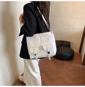 Detail view of white large tote bag with dual front flap pockets and metallic fasteners
