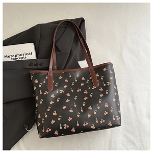 Flat lay of cherry print tote bag with brown straps and a stylish black blazer
