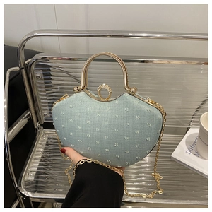 Detail of light blue denim chain bag with golden handle and heart-shaped texture
