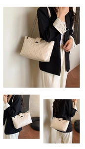 Detailed view of cream quilted tote bag with golden metal chain strap and twist lock closure
