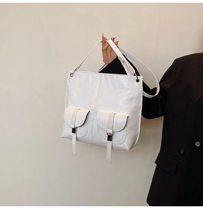 Détail du cabas en cuir blanc avec doubles poches symétriques et boucles métalliques
