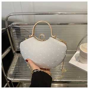 Macro detail of white textured chain bag with golden handle and rhinestone buckle