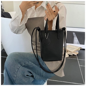 Close-up of black lychee texture mini tote bag with smile charm and slim shoulder strap