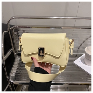 Detail of light yellow leather bag featuring a gold rectangular twist lock closure