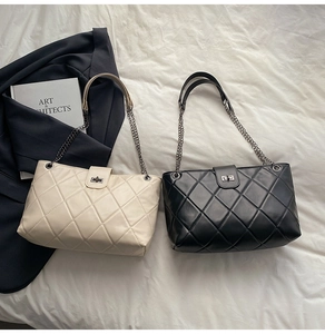 Detail of quilted tote bags in black and cream white with metal chain straps and twist locks