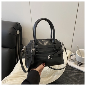 Detail of glossy black shell bag with silver buckles and decorative belt straps