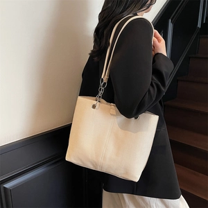 Minimalistische beige Shopper-Tasche mit Kettenriemen am Modell in Büro-Umgebung