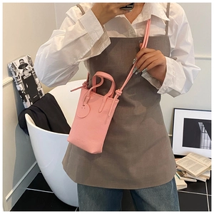 Detail of pink faux leather crossbody phone bag with litchi texture and metal charm