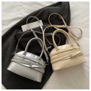 Macro view of metallic silver and beige faux leather shell bags with buckle straps