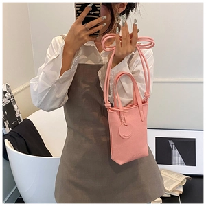 Close-up of pink pebbled leather crossbody bag with Smiley Lucky charm in home setting