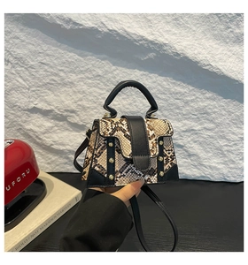 Detail of snake print leather mini bag featuring golden rivets and black handle