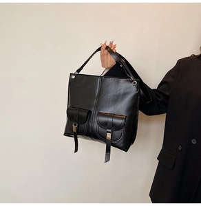 Vue détaillée du sac cabas noir avec deux poches frontales et détails de boucles en métal