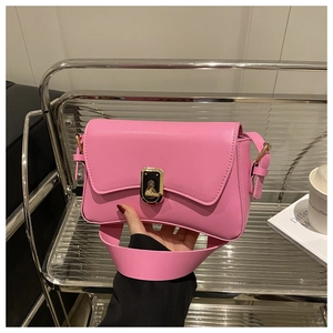 Detail of pink leather baguette bag featuring a gold twist lock and wide shoulder strap