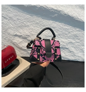 Detail view of pink snake print mini crossbody bag with golden rivet buckle and black handle