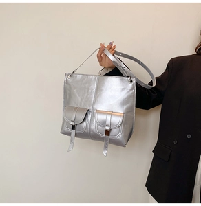 Détail du sac fourre-tout argenté avec poches à boucles devant sur un blazer noir élégant
