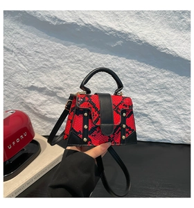 Detail of red and black snakeskin texture bag with gold rivets and black top handle