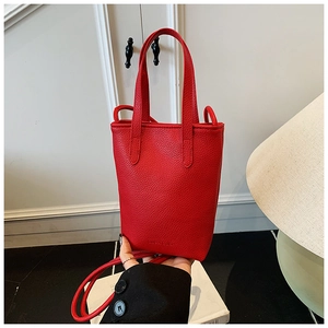 Close-up of vibrant red pebbled leather tote bag with handle and subtle debossed logo
