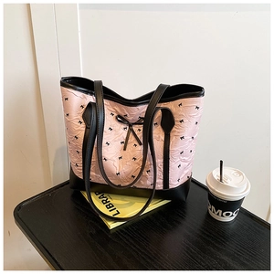 Detail of pink crinkled fabric tote with black bow prints and leather shoulder straps